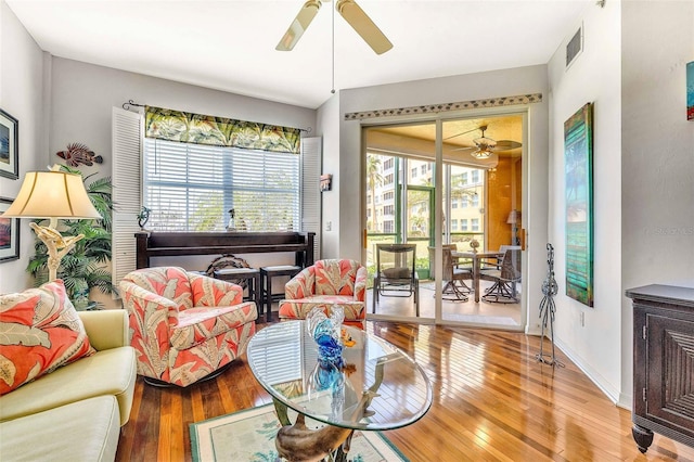 living area featuring a ceiling fan, baseboards, visible vents, and light wood finished floors