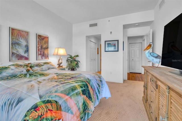 bedroom featuring light colored carpet, visible vents, and a closet