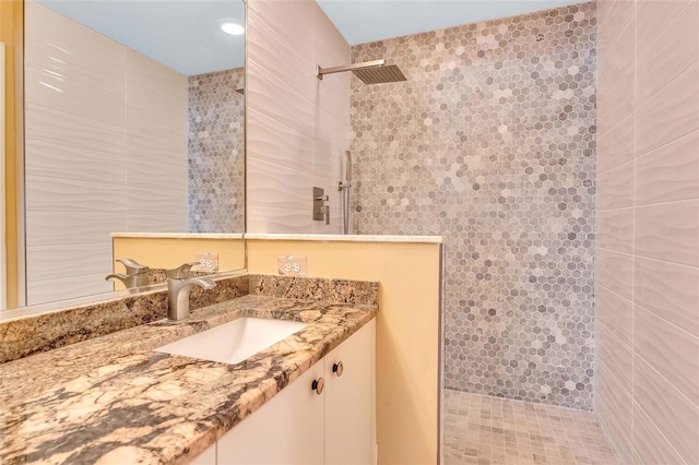 full bath with vanity, a walk in shower, and tile walls