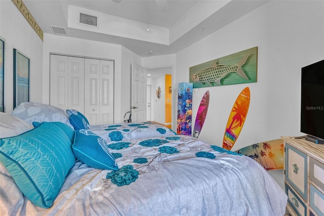 bedroom with ceiling fan, visible vents, a tray ceiling, and a closet