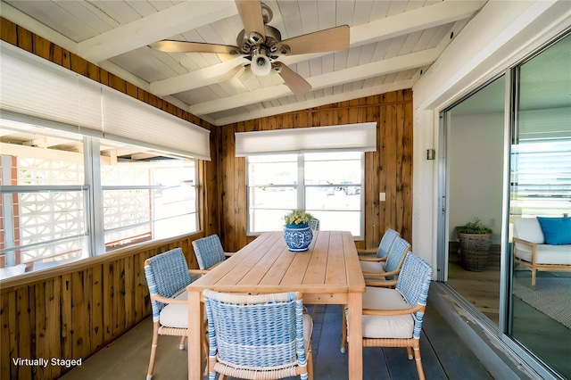 dining space with wooden walls and a ceiling fan