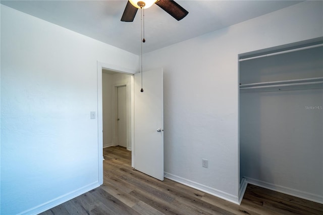 unfurnished bedroom featuring wood finished floors, baseboards, and a closet