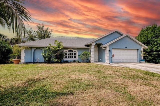view of front of property with a lawn, driveway, a garage, and stucco siding