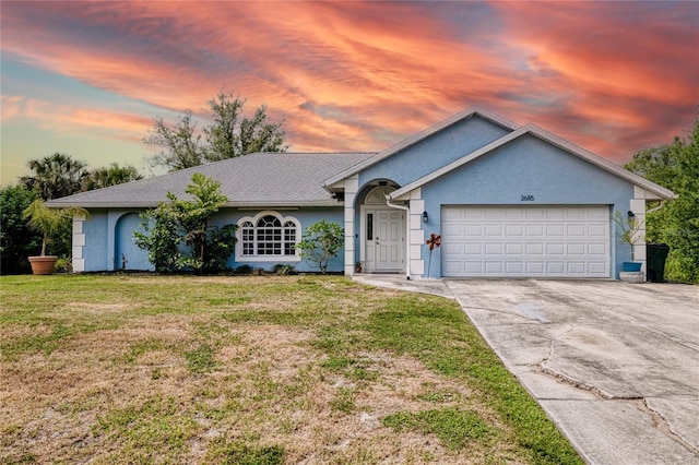ranch-style home with concrete driveway, a yard, an attached garage, and stucco siding