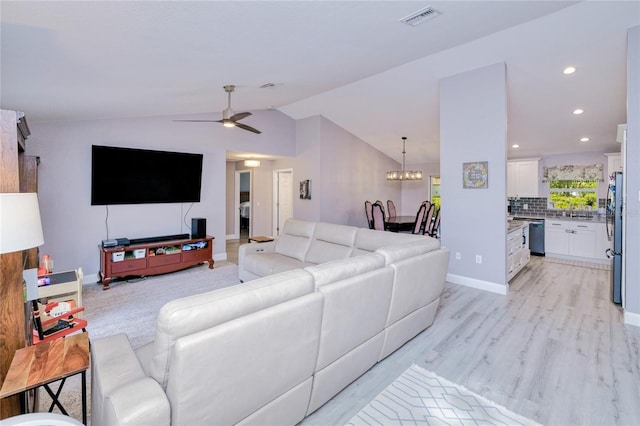 living area featuring vaulted ceiling, visible vents, light wood-type flooring, baseboards, and ceiling fan with notable chandelier