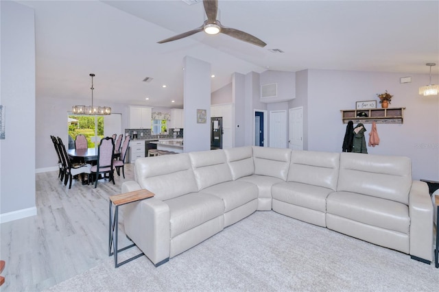 living area with vaulted ceiling, ceiling fan with notable chandelier, light wood-style floors, baseboards, and visible vents