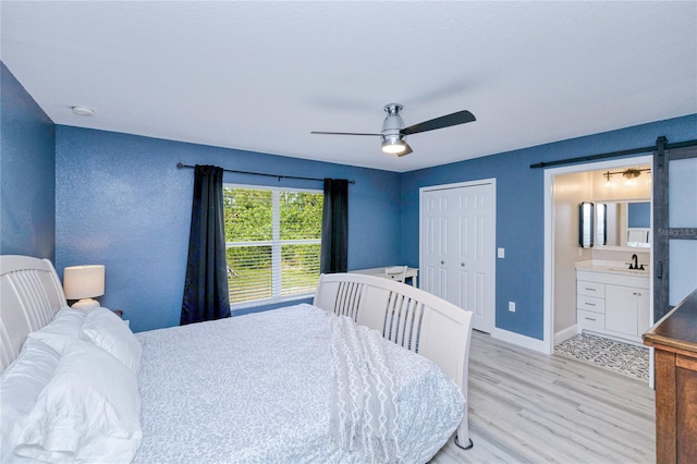 bedroom featuring a sink, baseboards, light wood-style floors, a closet, and ceiling fan