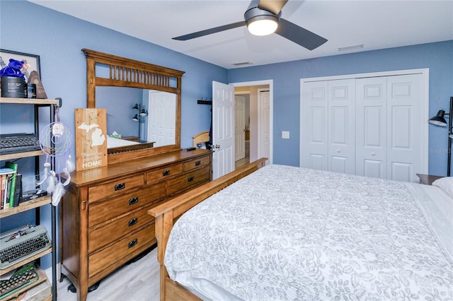 bedroom featuring ceiling fan, wood finished floors, visible vents, and a closet