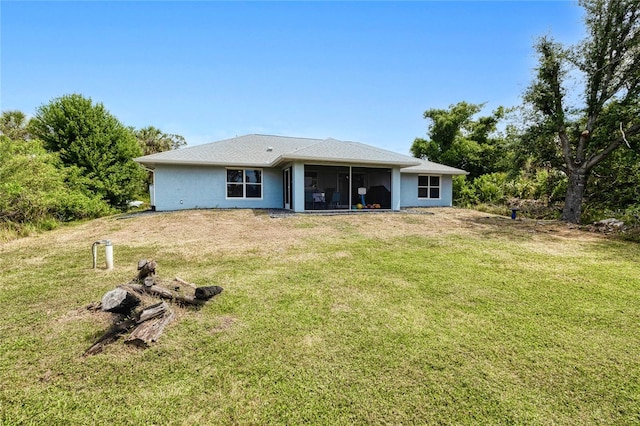 rear view of house featuring a sunroom and a lawn