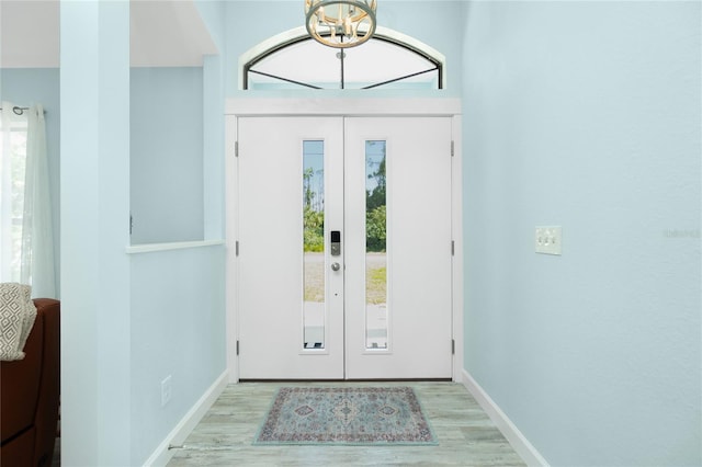 entrance foyer featuring baseboards, a notable chandelier, and wood finished floors