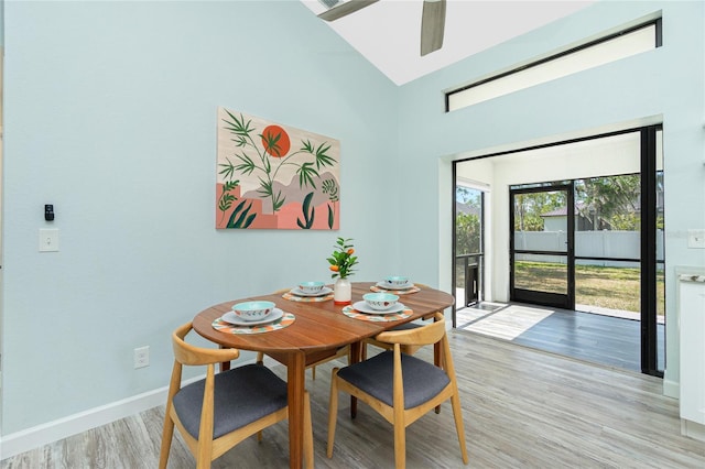 dining area featuring light wood-style flooring, high vaulted ceiling, ceiling fan, and baseboards