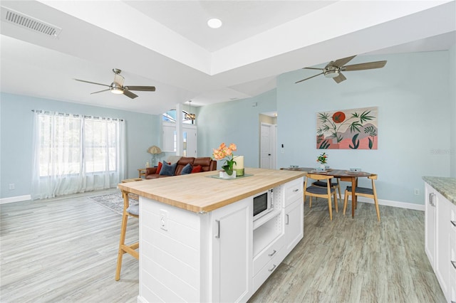 kitchen with visible vents, open floor plan, wooden counters, ceiling fan, and white microwave