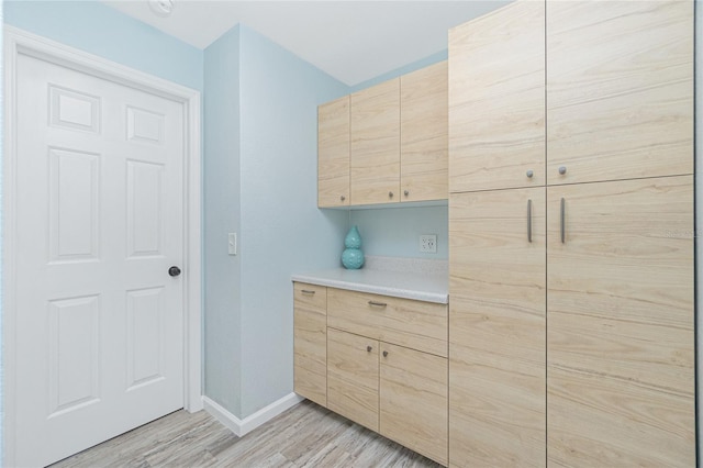 laundry room featuring light wood finished floors and baseboards