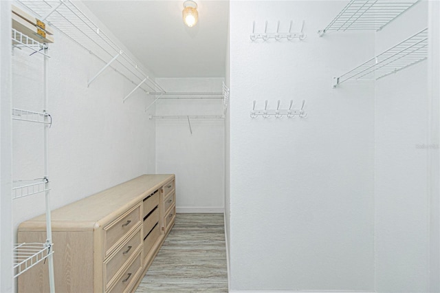 walk in closet with light wood-style flooring