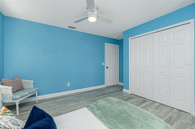 bedroom featuring visible vents, a closet, baseboards, ceiling fan, and wood finished floors