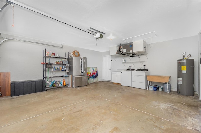 garage with electric water heater, a garage door opener, washer and clothes dryer, and freestanding refrigerator