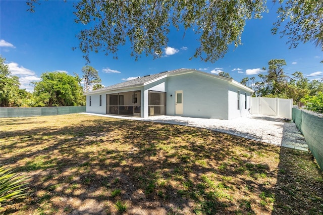 rear view of house featuring a fenced backyard, a gate, a sunroom, and stucco siding