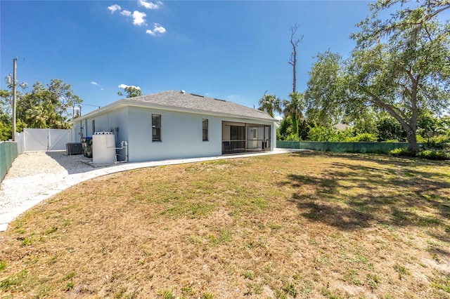 rear view of house featuring cooling unit, a sunroom, a yard, a fenced backyard, and a gate