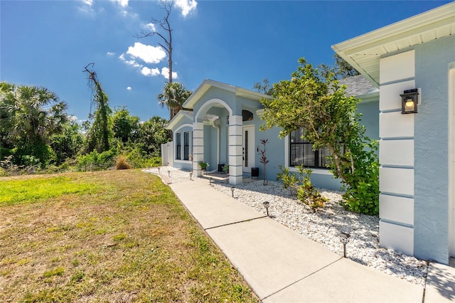 property entrance featuring a yard and stucco siding