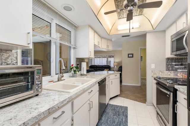 kitchen with stainless steel appliances, light countertops, a ceiling fan, a sink, and light tile patterned flooring