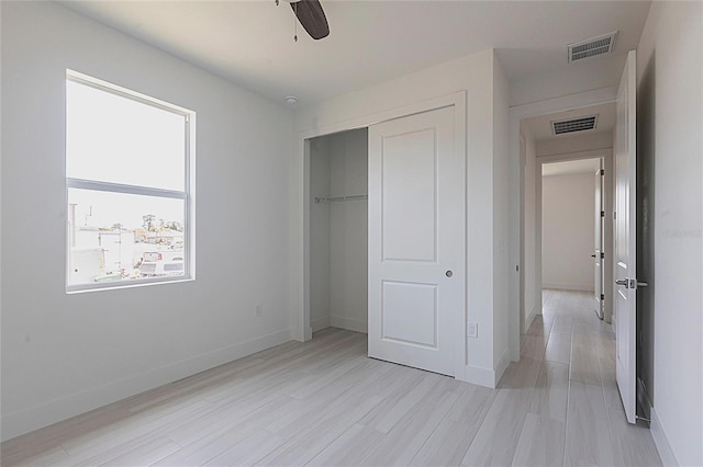 unfurnished bedroom with baseboards, visible vents, light wood finished floors, and a closet