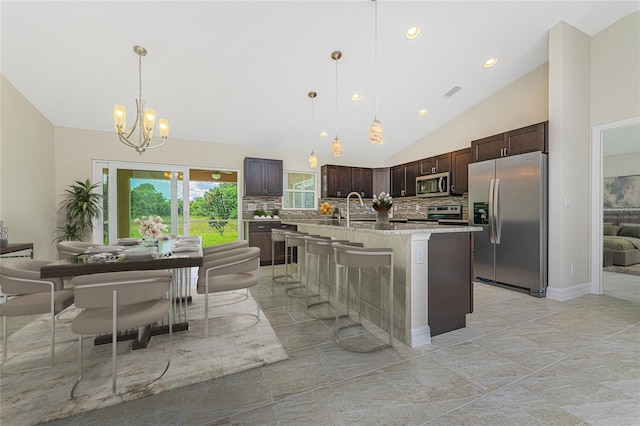 4336 Blackman St, North Port, FL 34291 - kitchen featuring stainless steel appliances, backsplash, vaulted ceiling, dark brown cabinetry, and a notable chandelier