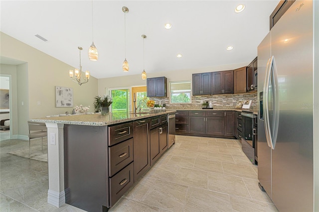 4336 Blackman St, North Port, FL 34291 - kitchen featuring an island with sink, appliances with stainless steel finishes, backsplash, lofted ceiling, and a notable chandelier