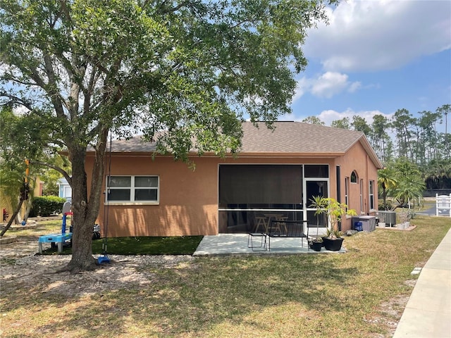 10740 Pearl Bay Cir, Estero, FL 33928 - back of house with central air condition unit, a shingled roof, a patio area, a yard, and stucco siding