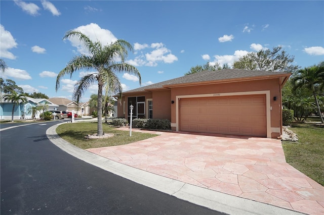 10740 Pearl Bay Cir, Estero, FL 33928 - view of front of property with stucco siding, driveway, a shingled roof, and a garage