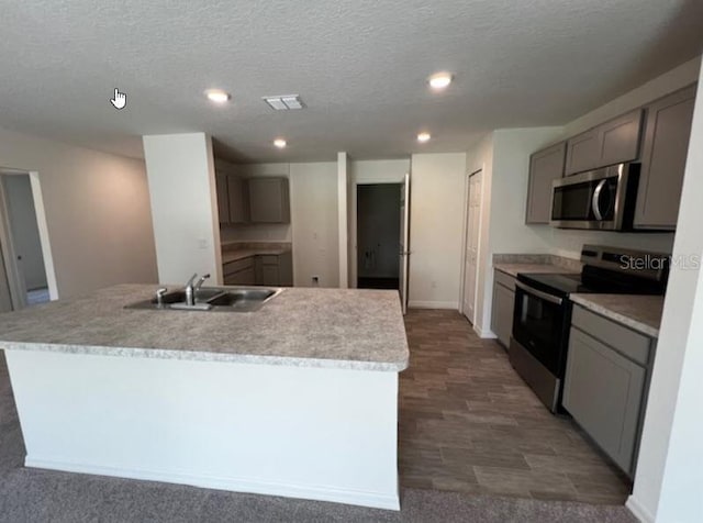 kitchen with an island with sink, stainless steel appliances, visible vents, gray cabinets, and a sink