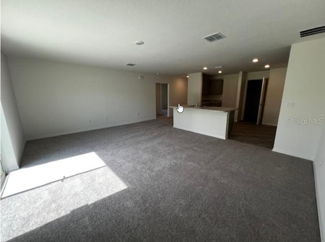 unfurnished living room featuring baseboards, visible vents, and carpet