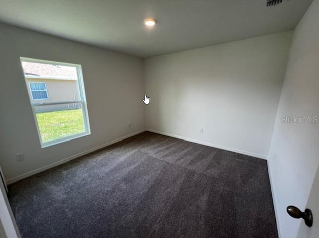 unfurnished room with baseboards and dark colored carpet