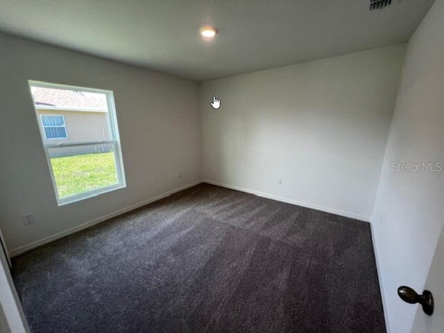 empty room with baseboards and dark colored carpet