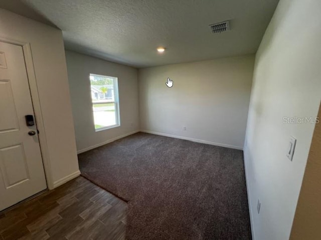 foyer entrance with a textured ceiling, baseboards, dark wood-style flooring, visible vents, and recessed lighting