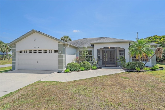 single story home with concrete driveway, a front yard, an attached garage, stucco siding, and french doors