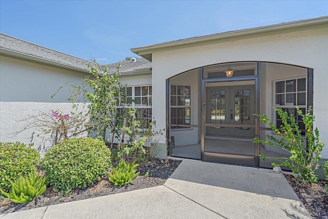 view of exterior entry featuring french doors and stucco siding