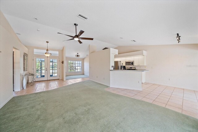 unfurnished living room featuring light tile patterned floors, visible vents, light colored carpet, french doors, and lofted ceiling