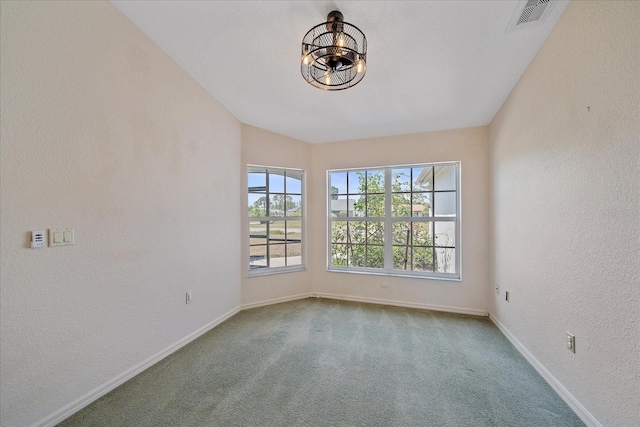 carpeted empty room with baseboards, visible vents, a notable chandelier, and a textured wall