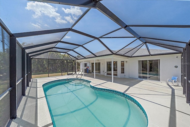 outdoor pool featuring glass enclosure and a patio area