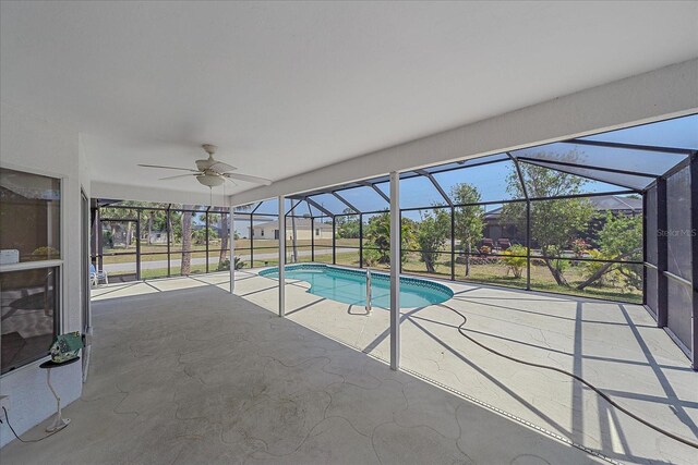 outdoor pool featuring a ceiling fan, glass enclosure, and a patio area