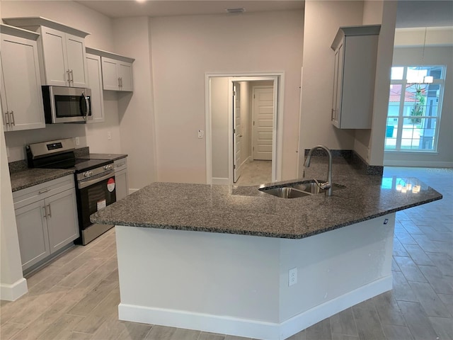 112 Cougar Way, Rotonda West, FL 33947 - kitchen with stainless steel appliances, dark stone counters, a peninsula, light wood finished floors, and gray cabinets