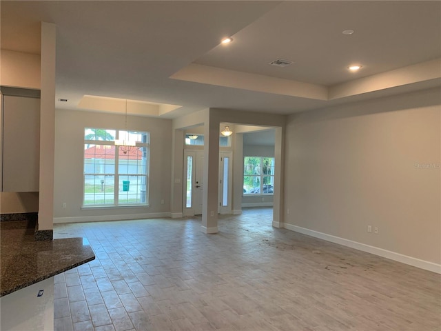 112 Cougar Way, Rotonda West, FL 33947 - unfurnished living room featuring a tray ceiling, light wood finished floors, a chandelier, and recessed lighting