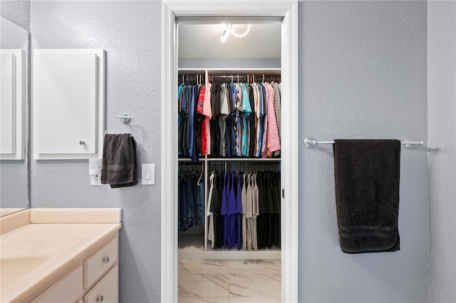 1773 Portage St, North Port, FL 34287 - bathroom featuring vanity, marble finish floor, and a walk in closet