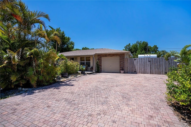 ranch-style home featuring fence, decorative driveway, and a garage