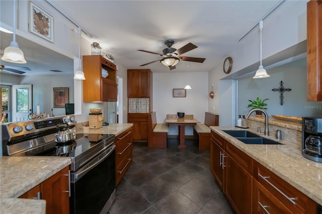 kitchen featuring light stone counters, a ceiling fan, a sink, brown cabinets, and stainless steel electric range