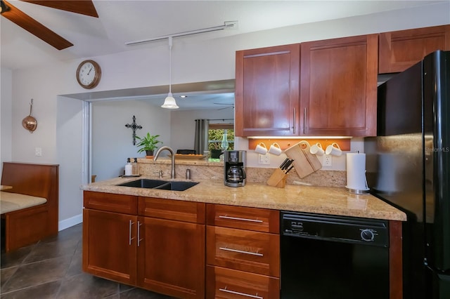 kitchen featuring a sink, light stone counters, dark tile patterned flooring, decorative light fixtures, and black appliances