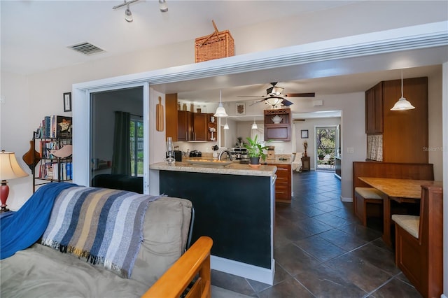 kitchen with light countertops, visible vents, a ceiling fan, decorative light fixtures, and a peninsula