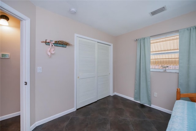 unfurnished bedroom with baseboards, tile patterned flooring, visible vents, and a closet