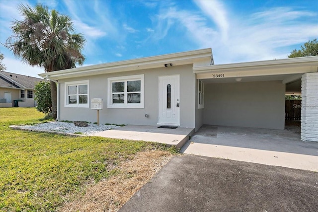 ranch-style house with stucco siding, driveway, a front yard, and a carport