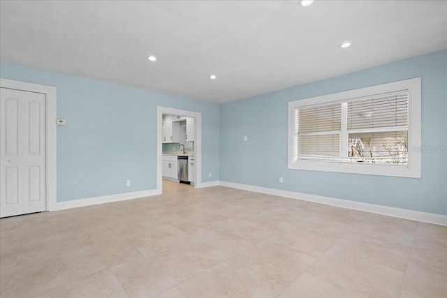 spare room featuring baseboards, a sink, and recessed lighting